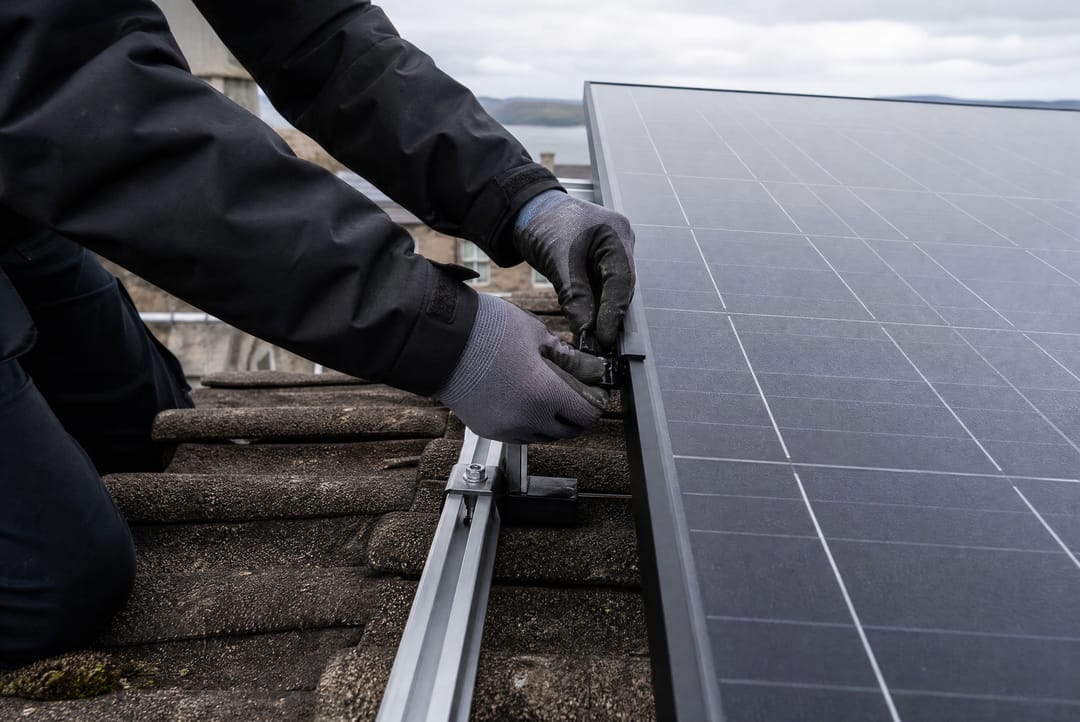 Installer fixing a black solar panel to roof rails